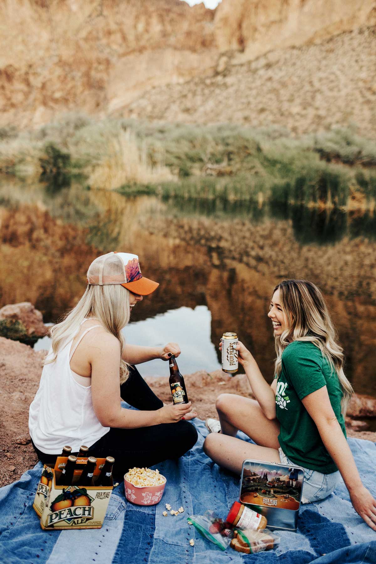 2 women drinking beer outdoors.